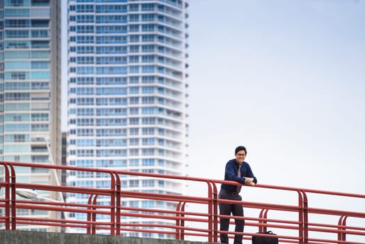 Portrait of chinese businessman standing and leaning on bridge in Panama. Skyscrapers in background
