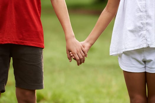 People in love with little girl and boy holding hands in park. Cropped view