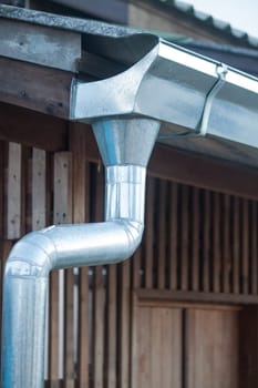 Aluminum rain gutter with wood house background