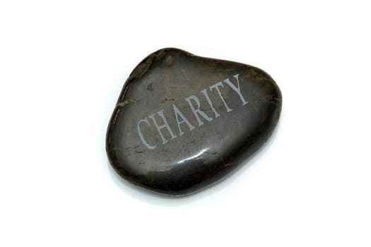 A smooth polished stone with the word Charity engraved in the top of it. Over white.