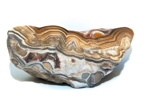 A layers and colorful cut and polished stone over white showing the various designs within. Over white.