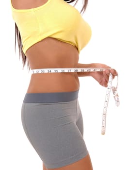 A slim teenager girl in exercise clothing measuring her stomach, .body part isolated over white background..