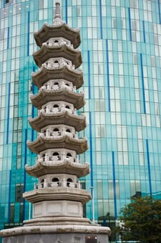 Chinese pagoda against a front of glas windows of a modern skyscraper