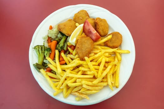 Fried chicken nuggets, French fries and vegetables