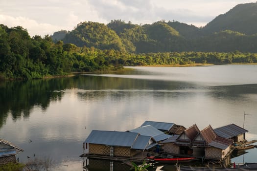Living houses floating on Khao Laem Lake nearby the thai town Sangkhla Buri at sunset. Surrounded by forests and lake this makes an idyllic surrounding.