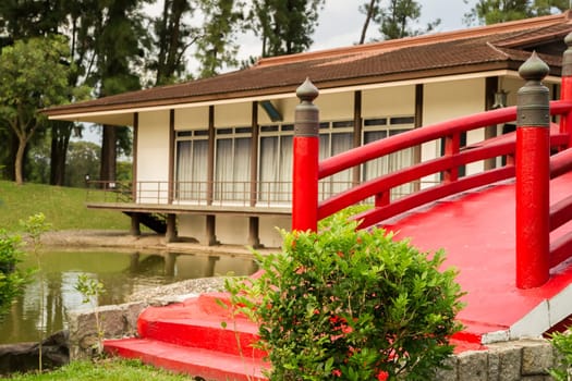 A wooden bridge across a small river in front of a traditional house. Japanese style.