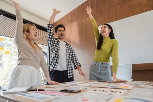 A diverse team joyfully celebrates their successful UX design ideas, highlighting collaboration and innovation in a contemporary workspace.