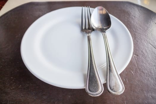 Top view of white plate with spoon and fork, stock photo