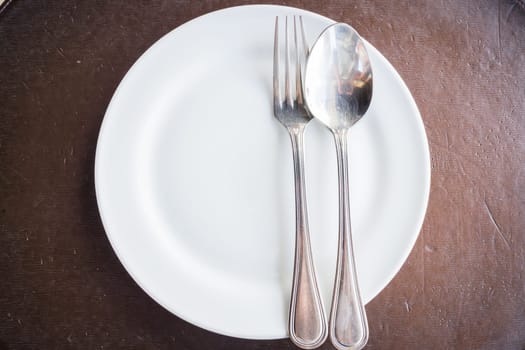 Top view of white plate with spoon and fork, stock photo