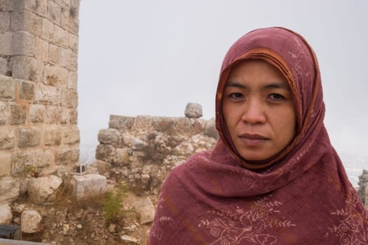 An asian lady with a scarf at the ruins of Ajloun Castle in Jordan
