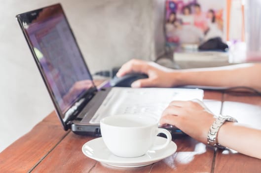 Woman using laptop with a cup of coffee, stock photo