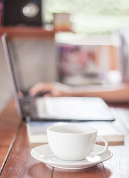Woman using laptop with a white cup of coffee, stock photo