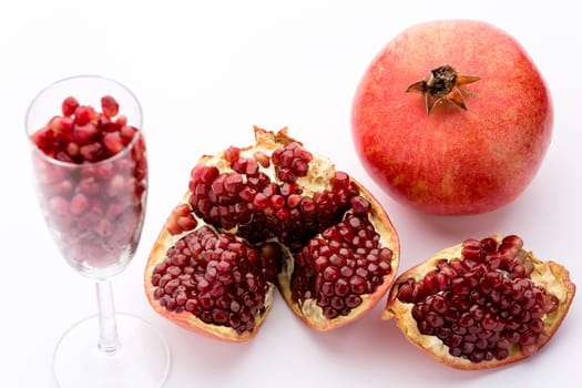 Ripe pomegranates, Punica granatum, broken open and whole. Seeds of this fruit in a champagne glass.