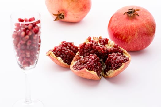 Broken paradise fruit with red,ripe cores in the core casing. Paradise fruit seeds in a champagne glass. Two whole fruits.