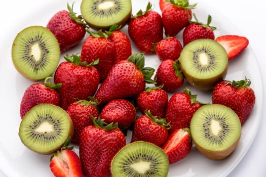 A plate full of strawberries and halved kiwis.