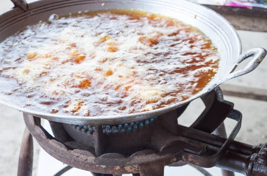 Chicken deep frying in hot oil in a cast iron frying pan