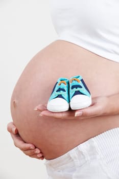 Close Up Of Pregnant Woman Holding Baby Shoes