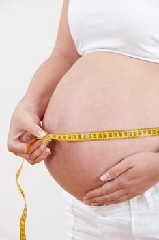 Close Up Of Pregnant Woman Measuring Waist