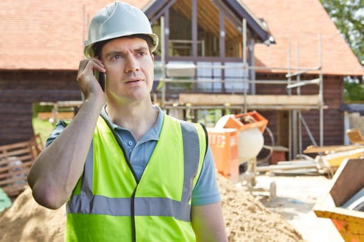 Construction Worker On Building Site Using Mobile Phone