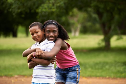 People in love with happy little black girl and boy hugging and embracing in city park