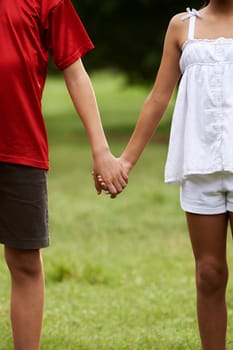 People in love with little girl and boy holding hands in park. Cropped view