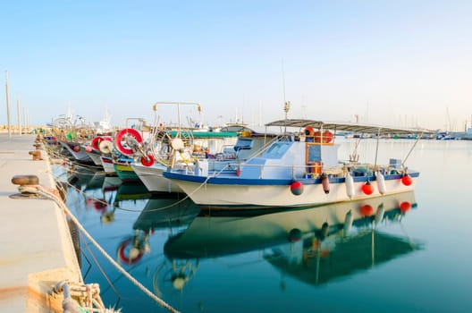Fishing boats docked at the Limassol old port in Cyprus, next to the Marina part of the ports authority. A view of the harbor, the mediterranean sea, the water, boat and fish nets and fishing equipment.