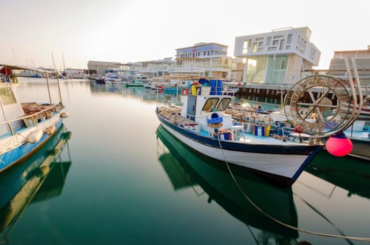 Fishing boats docked at the Limassol old port in Cyprus, next to the Marina part of the ports authority. A view of the harbor, the mediterranean sea, the water, boat and fish nets and fishing equipment.