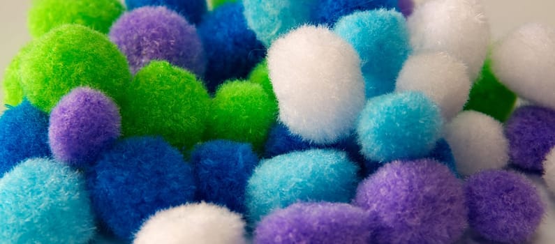A collection of colorful craft pompoms various colors up close.