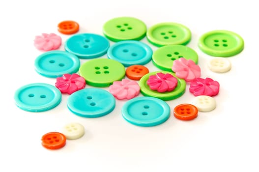 An assortment of shapes, sizes, and colors of buttons, round and flower shaped, shot over white.