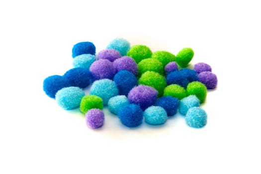 A collection of colorful craft pompoms shot over white of various colors.