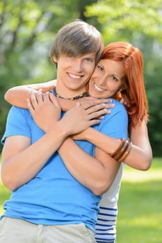 Young loving couple teenagers embracing and smiling in sunny park