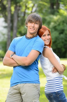 Teenage friends couple leaning against each other in sunny park