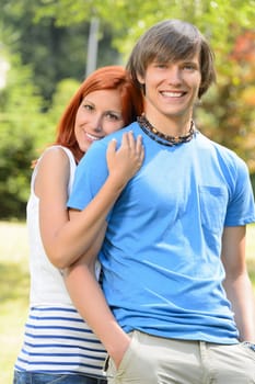 Loving teenage girlfriend embracing her boyfriend in sunny park
