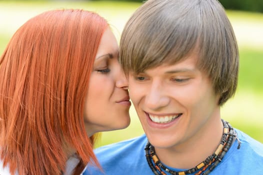 Loving young woman kissing boyfriend's cheek sunny day close-up