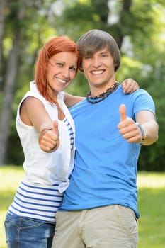 Teenage friends show thumb up in sunny park