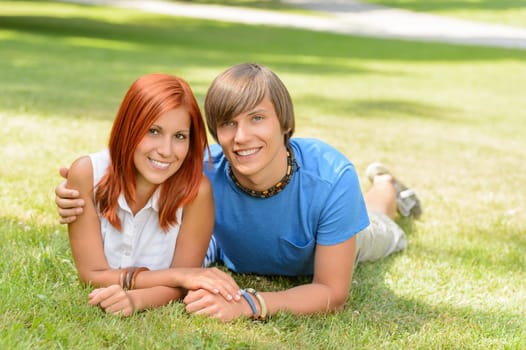 Teenage couple lying on grass summer love smiling at camera