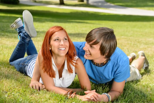 Teenage couple lying on grass laughing together enjoy summer day