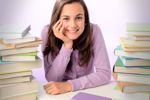 Smiling student girl sitting between stacks of books purple background
