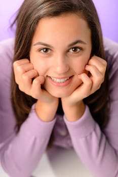 Teenage girl smiling at camera on purple close-up portrait