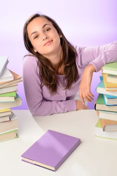 Confident student girl between stacks of books on purple background