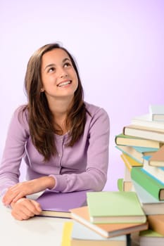 Smiling student girl stacks of books looking up purple background