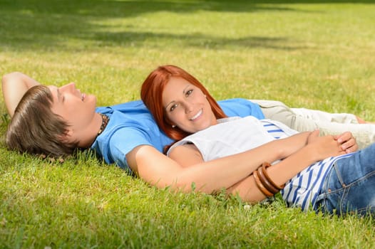 Teenage couple enjoying sun lying together on grass relaxing