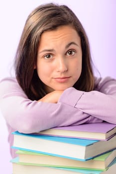Desperate student girl leaning on stack of books purple background