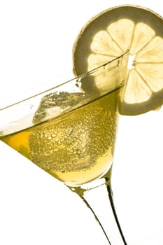 Glass with drink,ice cubes and lemon in yellow