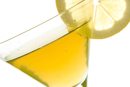 Glass with yellow drink and lemon in the backlight