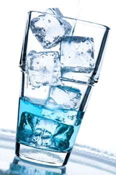 Glass with ice cube and blue drink in portrait format