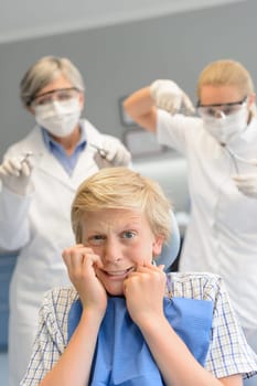Scared teenage boy at dental surgery dentist woman with assistant