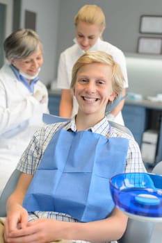 Dental team at stomatology clinic with teenager patient boy smiling