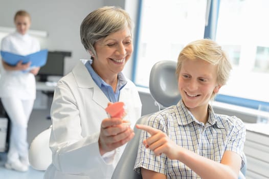 Teenage boy point teeth denture dentist checkup at dental surgery