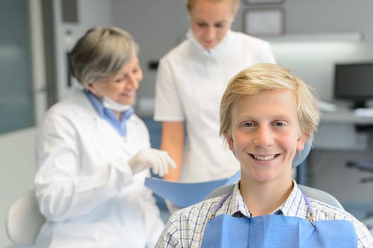 Teenage patient boy, dentist woman with dental assistant at stomatology clinic